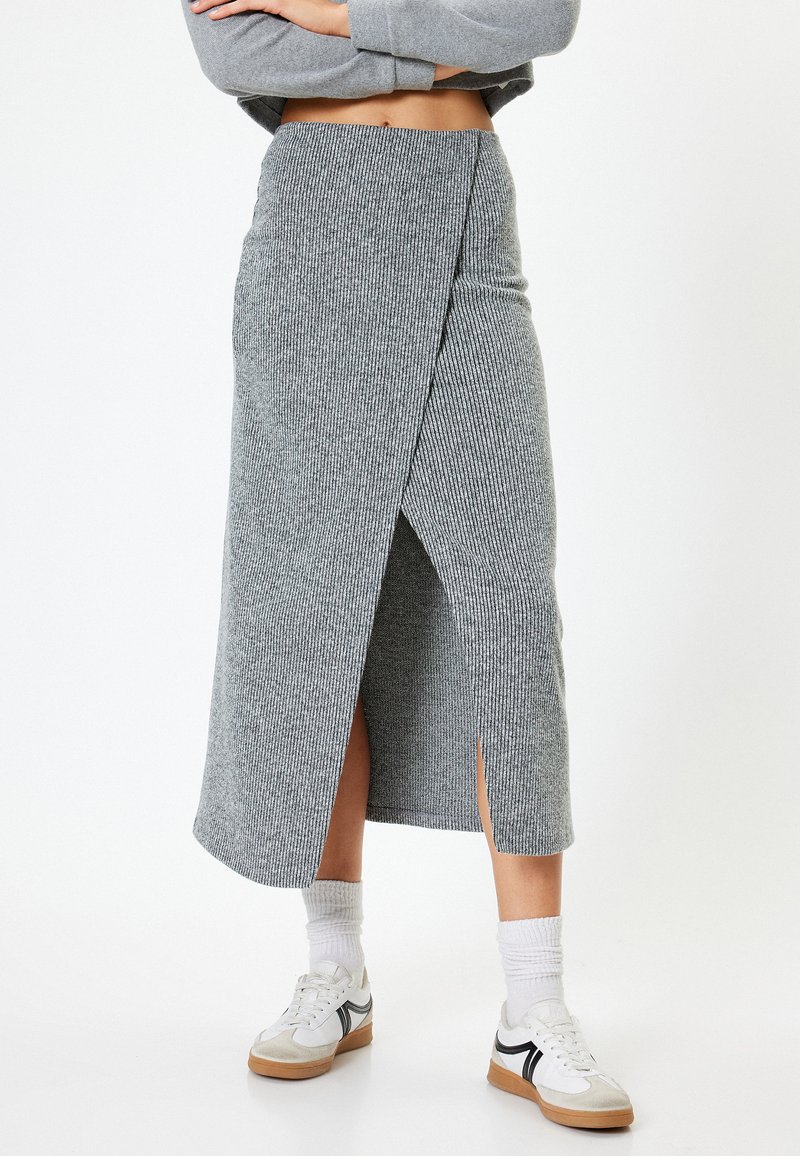 Gonna midi grigia a coste con design a portafoglio e spacchi laterali, abbinata a sneakers bianche e calze alla caviglia. Tessuto morbido e testurizzato.