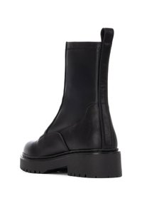 Botas de tobillo de cuero negro con suela de plataforma gruesa, textura suave, diseño sin costuras y una lengüeta trasera para facilitar su uso.
