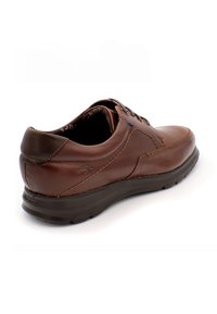 Zapato de piel marrón con punta redondeada, tacón marrón oscuro en contraste y suela de goma texturizada. Presenta cordones tradicionales y detalles de costura.