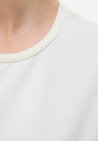 T-shirt grigio chiaro a maniche corte con scollatura rotonda, realizzato in morbido cotone, con una semplice cucitura lungo il colletto.