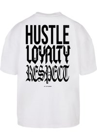 Balts kokvilnas T-krekls ar izteiksmīgu melnu grafisku tekstu aizmugurē: "HUSTLE LOYALTY RESPECT". Rāvējslēdzēja apakšdaļa un īsas piedurknes.