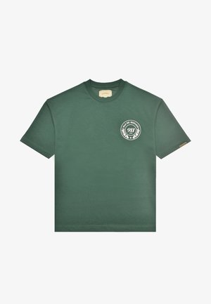 Maglietta verde scuro a maniche corte con collo rotondo, piccolo logo circolare bianco con la scritta "Pas de Monaco 911 Club" sul lato sinistro del petto.
