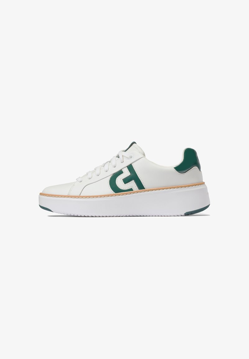 Vita lädersneaker med gröna accenter, rund tå och tjock vit sula. Har snörning och en logo på sidan. Texturerade detaljer på hälen.