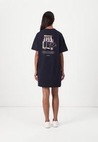 Marineblaue Kurzarmkleid mit einem grafischen Druck eines Ladens mit Blumen auf dem Rücken. Der Stoff wirkt weich und hat eine lockere Passform.