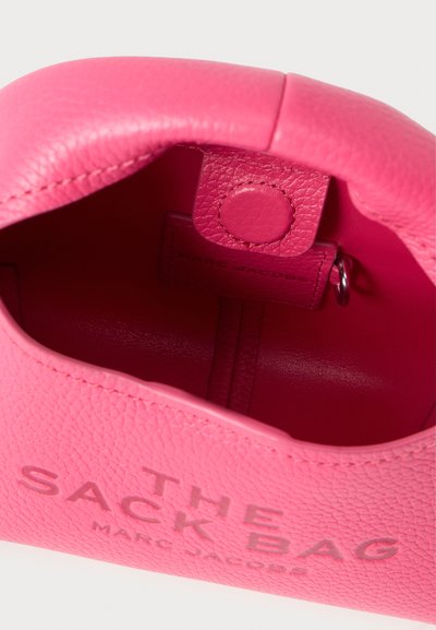 Rozā teksturētas ādas somas iekšpuse ar aizdares sprādzi un debossētu zīmolu "THE SACK BAG" gaišākā tonī. Gluda virsma.
