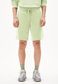 Lichtgroene katoenmix shorts, relaxed fit, met een drawstring taille, knielang, gecombineerd met grijze sneakers en lichtgroene sokken.