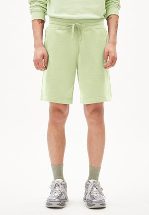 Helle grüne Baumwollshorts, lässige Passform, mit Kordelzugbund, knielang, kombiniert mit grauen Turnschuhen und hellgrünen Socken.