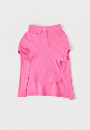 Polo rose vif à manches courtes avec deux boutons et fentes sur les côtés, posé à plat sur un fond blanc.