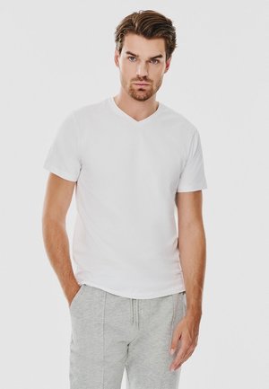 Biała koszulka V-neck wykonana z bawełny, z krótkimi rękawami, dopasowany krój. Połączona z jasnoszarymi dresami, z elastycznym pasem.