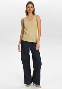 Beige sleeveless top paired with dark blue wide-leg jeans. The top features a rounded neckline, and the jeans have a straight cut with a hem.