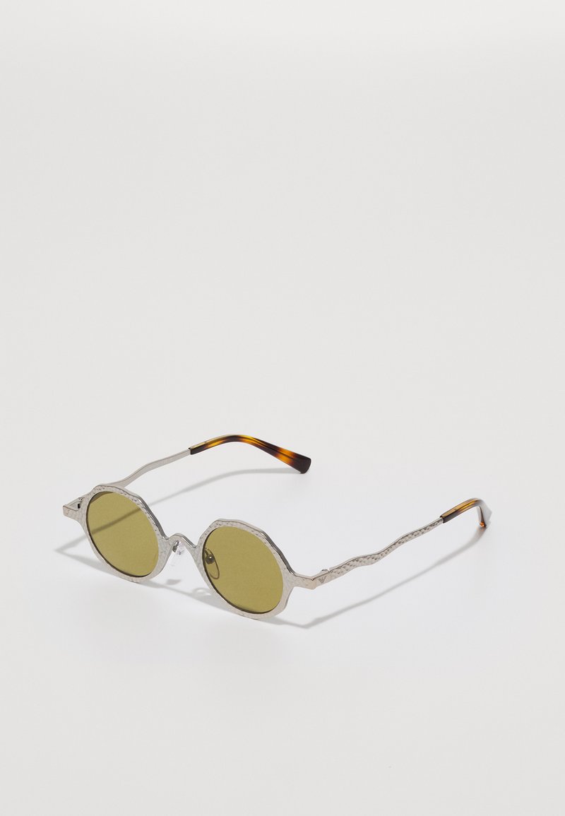 Ochelari de soare rotunzi cu lentile verzi măslinii, ramă metalică argintie cu un design texturat și țâțele cu model de țestoasă.