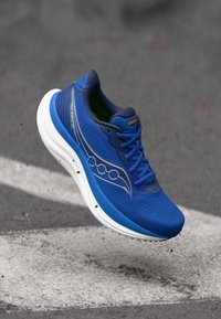 Blue athletic shoe with a textured mesh upper, white midsole, and rubber outsole. Features branding and reflective accents.