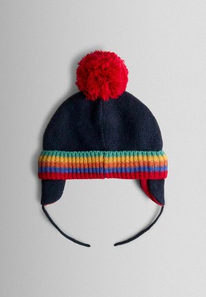 Pletená čepice v námořnické modři s červeným bambulí, se širokým proužkovaným lemem v červené, zelené, žluté a modré barvě. Součástí jsou ušní klapky a šňůrky.