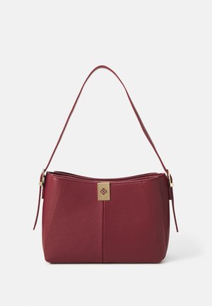 Pequeño bolso rectangular burdeos con una sola correa y un cierre rectangular en tono dorado que presenta un diseño recortado, sobre un fondo blanco.