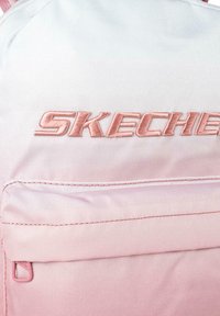 Mochila Skechers en tejido de color rosa degradado con textura suave, que presenta un logo bordado en un rosa más oscuro. Incluye un bolsillo frontal.