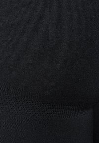 Tessuto nero a maglia con una texture a costine e una finitura liscia. Include un'area decorata con piccole perforazioni.