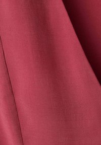 Tissu rose foncé lisse avec une texture de tissage fine et des plis doux créant des ombres douces et de la profondeur.