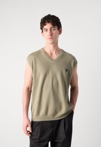 Pullover verde tricotado sem mangas com decote em V, apresentando detalhes em canelado na frente e um pequeno logótipo no peito.