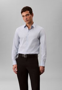 Hele sinine pikakäisega kleit-särk terava kraega, nööpidega ees ja peene kaubamärgiga. Sobitatud mustade pükste ja musta vööga.