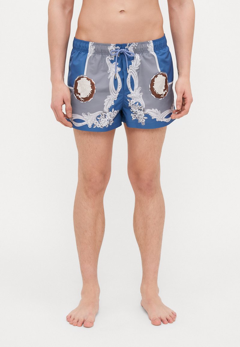 Shorts de bain gris et bleu avec des motifs floraux blancs ornés et des accents marron. Présente une taille élastique et un cordon de serrage.