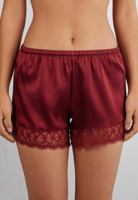 Pantalones cortos burdeos de satén suave, con un volante de encaje en el dobladillo. Cintura elástica para un ajuste cómodo.