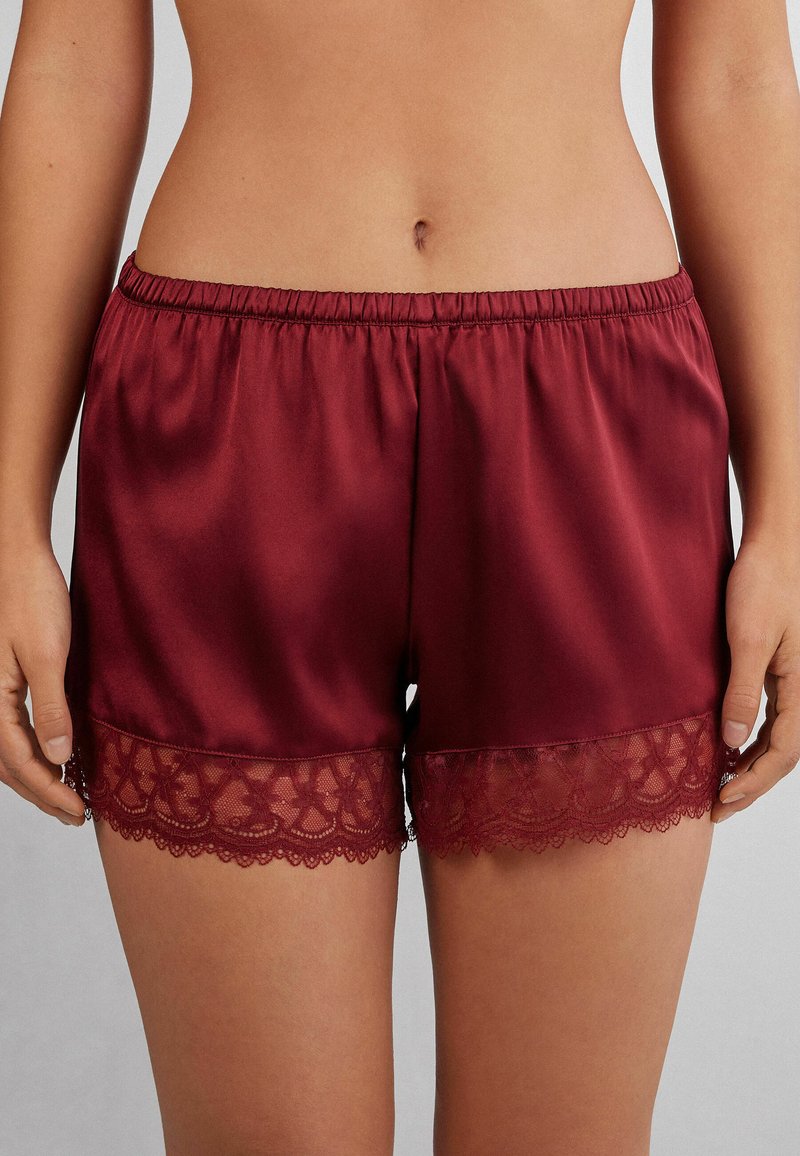 Pantalones cortos burdeos de satén suave, con un volante de encaje en el dobladillo. Cintura elástica para un ajuste cómodo.