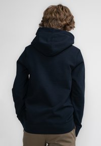 Navyblauwe hoodie van zachte stof, met een grote capuchon, kangoeroezak en ribgebreide manchetten en zoom. Eenvoudig ontwerp zonder zichtbare logo's.