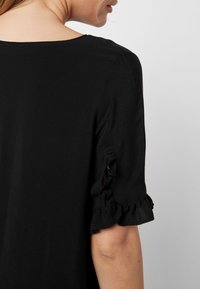 Zwarte top met een ronde halslijn, korte mouwen met gerimpelde accenten en een soepele textuur. Eenvoudig en minimalistisch ontwerp.