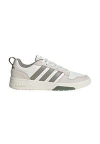 Baskets basses Adidas blanches et beiges avec le logo trois bandes gris, fermeture à lacets et semelle rembourrée.