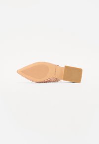 Zapato rosa de punta afilada con una parte superior texturizada cubierta de pequeños remaches, un tacón plano y una suela lisa.