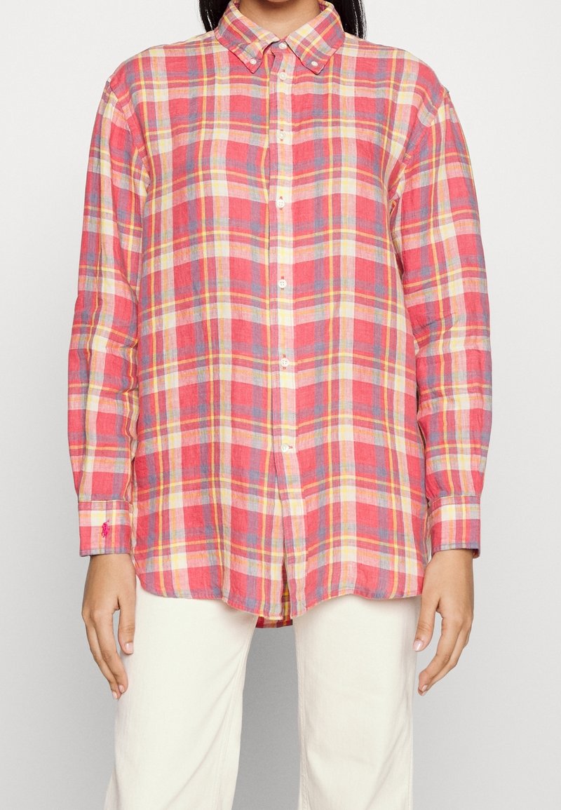 Červeno-žlutá kostkovaná košile s dlouhým rukávem, se zapínáním na knoflíky a lehkým materiálem. Má manžety na rukávech, zakřivený lem a volný střih.