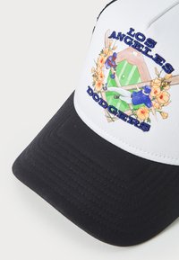 Hvid og sort kasket med broderet "Los Angeles Dodgers"-tekst, blomsteraccenter og illustrative baseballgrafikker på frontpanelet.