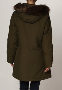 Parka vert olive avec une capuche bordée de fourrure, des manches longues, une taille cintrée et une coupe mi-longue, conçue pour la chaleur et le confort.
