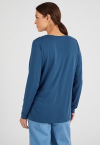 Langsleeve top in diepblauw, gemaakt van zachte stof. Beschikt over een ronde halslijn en een ontspannen pasvorm, met een soepele textuur en een minimaal ontwerp.