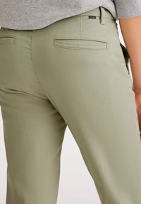 Olivgröna byxor i slät tyg, med två bakfickor och en elegant design med en något skräddarsydd passform.