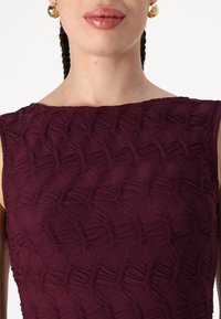 Burgundy ujjatlan ruha, textúrált anyaggal és szőtt mintázattal, kerek nyakkivágással és sima felülettel.