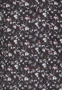 Camicia floreale con sfondo scuro, caratterizzata da piccoli fiori bianchi, viola e rossi. Chiusura frontale con bottoni rotondi viola.