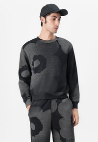 Schwarzer und grauer sweatshirt mit floralem Muster, langen Ärmeln und Rundhalsausschnitt, kombiniert mit passenden Hosen, die in einem lässigen Schnitt gestaltet sind.