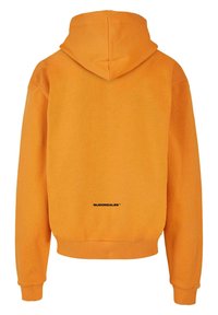Orange hoodie with a soft texture. Features a classic hood, ribbed cuffs, and a printed logo on the lower back.