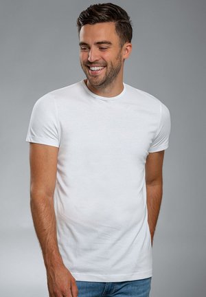 Witte t-shirt met korte mouwen, gemaakt van lichte stof, met een ronde halslijn en een getailleerd ontwerp, gecombineerd met blauwe spijkerbroeken.