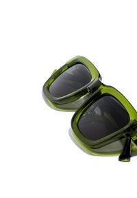 Ochelari de soare verzi, supradimensionați, cu o finisare lucioasă, formă pătrată și lentile închise la culoare. Accent subtil pe brațe. Material plastic ușor.