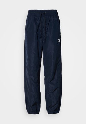 Tengerészkék széldzseki nadrág, fényes szintetikus anyagból készült, rugalmas derékrésszel és húzózsinórral, cuffolt szegélyekkel és logóval díszítve.