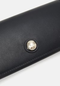 Portafoglio in pelle blu navy con finitura testurizzata, dotato di una chiusura a scatto in metallo prominente e bordi cuciti per garantire durata.