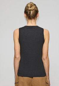 Top nero senza maniche con texture a costine, scollatura rotonda e forma aderente. Tessuto liscio con una leggera lucentezza e design semplice.