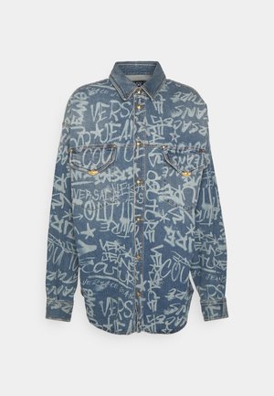 Denim shirt met een lichtblauwe basis, voorzien van witte graffiti-achtige tekst, knoopsluiting aan de voorkant, twee borstzakken en een klassieke kraag.