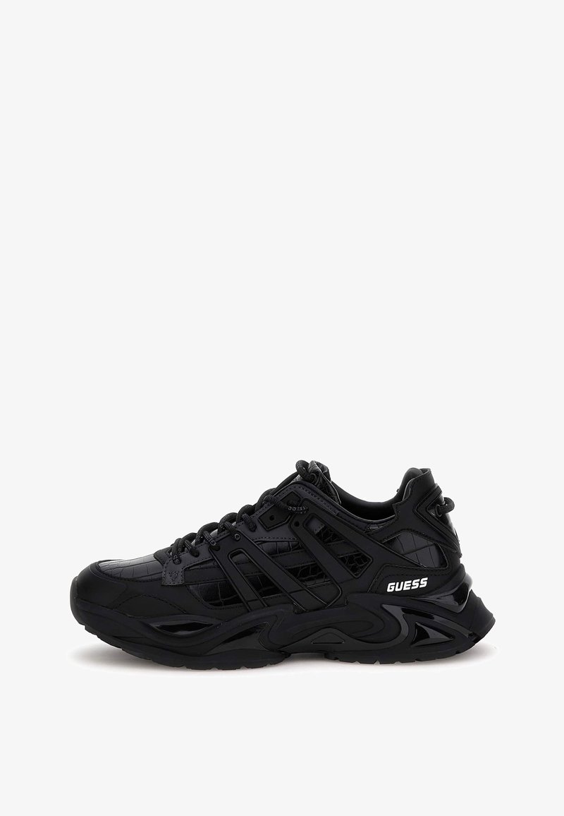 Baskets noires épaisses avec panneaux texturés, semelle épaisse, fermeture à lacets et logo "GUESS" sur le côté du talon.