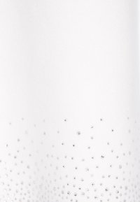 Bílá tkanina s hladkým povrchem, která má na spodní části gradient malých stříbrných kamínků, seskupených v různých velikostech.