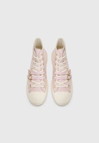 Sneakers înalte din pânză roz moale cu tălpi din cauciuc alb. Dispune de accente cu curea dublă și șireturi albe. Textură netedă.