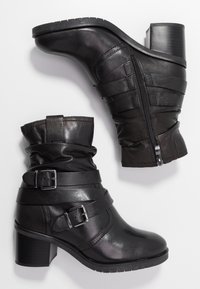 Black leather ankle boots with a chunky heel, featuring slouched tops, buckled straps, and a side zipper for easy wear.