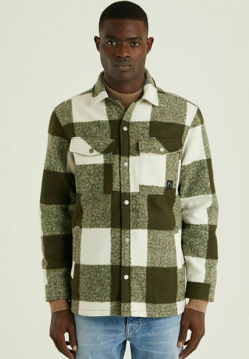 Groene en witte geruite flanellen shirt met twee borstzakken, drukknoopsluitingen en gebreide manchetten. Gemaakt van zachte, gestructureerde stof.